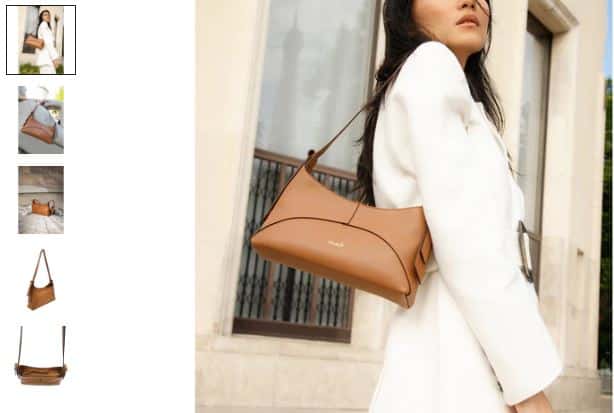 A woman in a white coat holds a tan Ambre Desserto® Cactus Leather Vegan Baguette Bag.