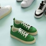 A collection of stylish sneakers displayed on a light blue background. The sneakers include a variety of designs and colors, with a prominent green pair with white laces in the center. Other sneakers in the image include white, black, and combinations of white with black or colored accents, arranged in a scattered yet aesthetically pleasing manner.