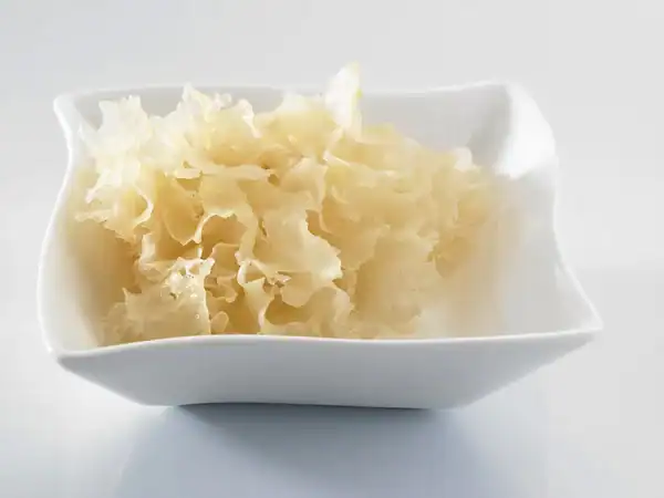 Fresh white snow fungus (Tremella fuciformis) served in a white bowl, showcasing its ruffled, translucent texture for cooking and beauty benefits.