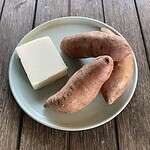 Sweet potatoes and a block of butterkäse cheese on a plate, ingredients used to analyze the nutritional value of the Butterkäse sweet potato recipe.